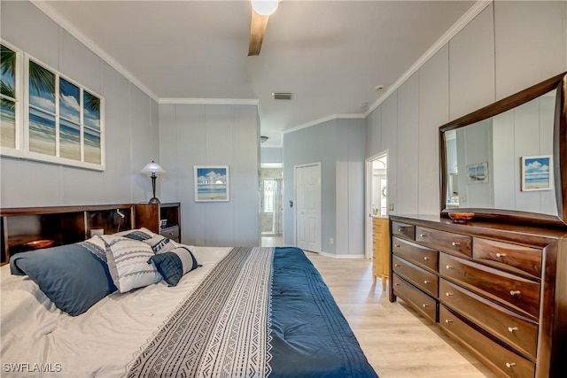 bedroom with a decorative wall, visible vents, light wood finished floors, and ornamental molding