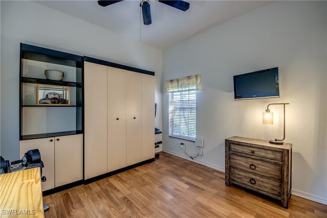 bedroom featuring a ceiling fan, a closet, baseboards, and wood finished floors