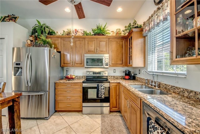 kitchen featuring appliances with stainless steel finishes, light tile patterned flooring, a sink, and light stone counters