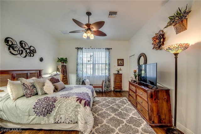 bedroom featuring a ceiling fan, visible vents, baseboards, and wood finished floors