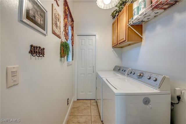 laundry room featuring cabinet space, baseboards, washer and clothes dryer, and light tile patterned flooring