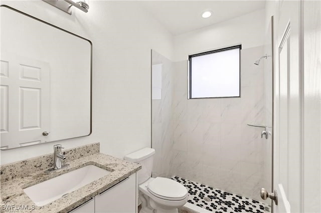 bathroom with vanity, a tile shower, and toilet