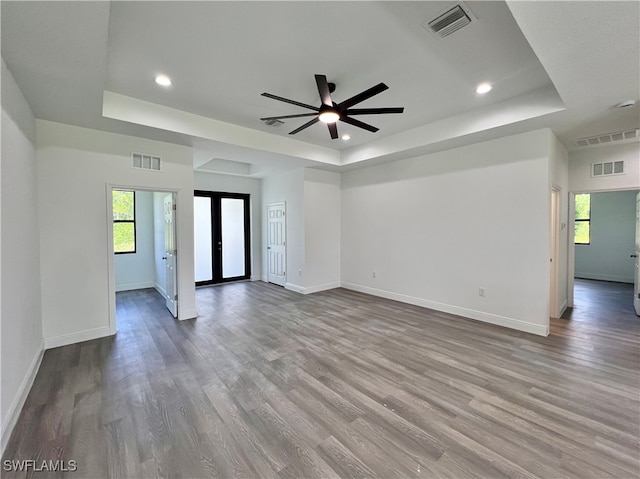 empty room with french doors, a tray ceiling, wood-type flooring, and ceiling fan