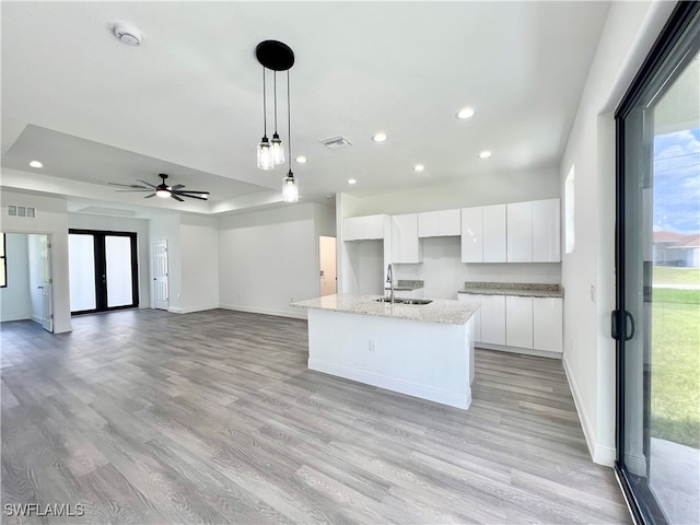 kitchen featuring a center island with sink, sink, white cabinetry, and light hardwood / wood-style floors