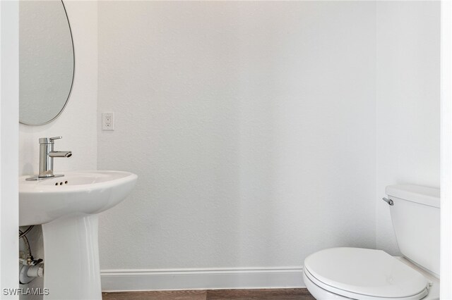 bathroom with hardwood / wood-style flooring, toilet, and sink