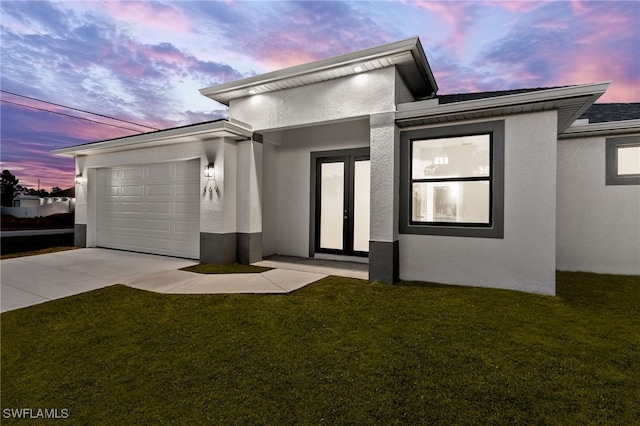 view of front of property with a garage and a lawn