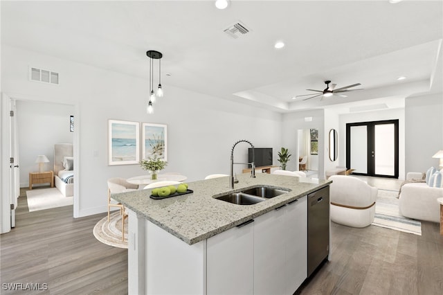 kitchen featuring pendant lighting, sink, dishwasher, an island with sink, and white cabinets