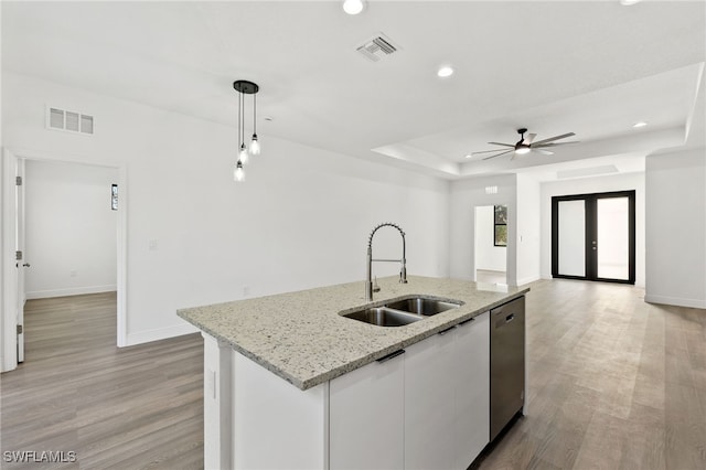 kitchen with decorative light fixtures, dishwasher, an island with sink, sink, and white cabinets