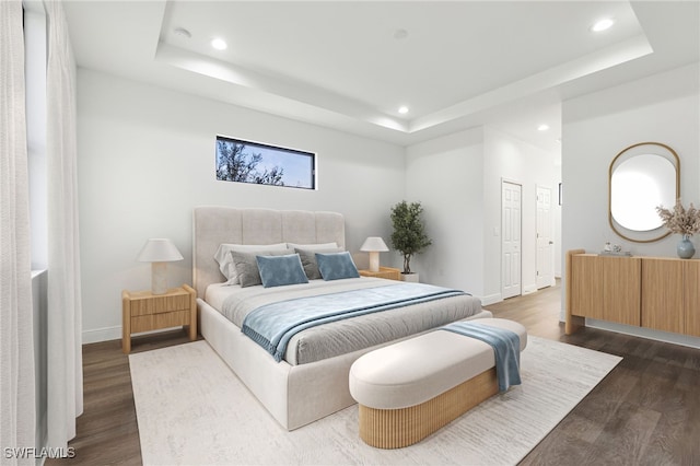 bedroom with dark hardwood / wood-style floors and a tray ceiling