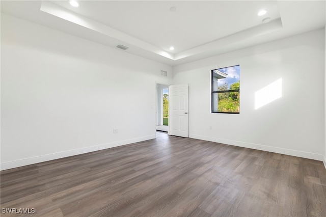 unfurnished room with a raised ceiling and dark hardwood / wood-style flooring