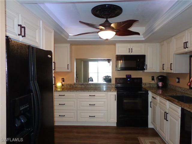 kitchen with black appliances, white cabinetry, and a tray ceiling