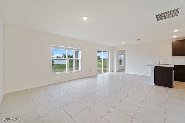 unfurnished living room featuring sink and light tile patterned floors