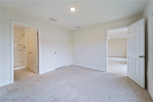 unfurnished bedroom featuring light carpet and ensuite bath