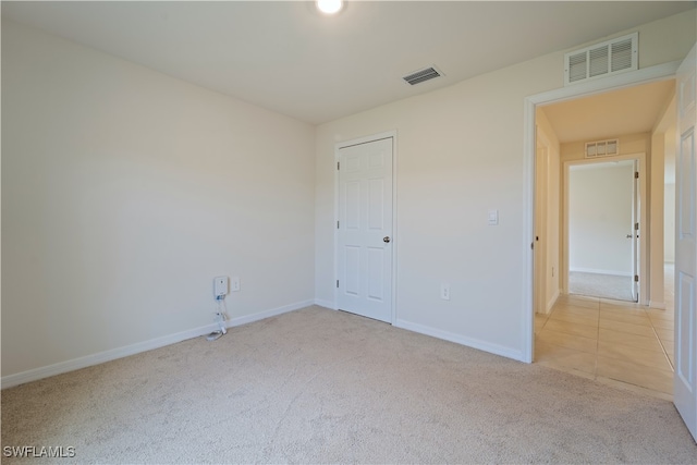 unfurnished bedroom with light carpet and a closet