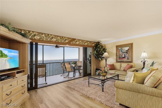 living room with crown molding, a water view, and light wood-type flooring