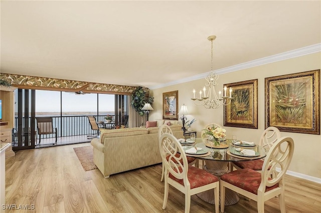 dining room featuring an inviting chandelier, ornamental molding, a water view, and light hardwood / wood-style flooring