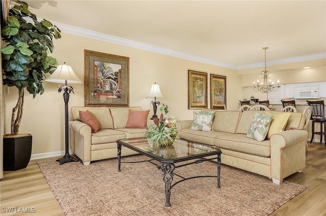 living room featuring light wood-type flooring, a notable chandelier, and ornamental molding