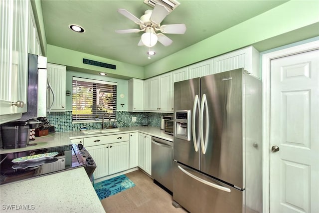 kitchen with light wood finished floors, decorative backsplash, stainless steel appliances, light countertops, and a sink