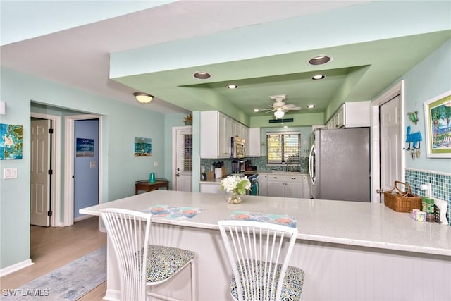 kitchen featuring a peninsula, appliances with stainless steel finishes, white cabinetry, and light stone countertops