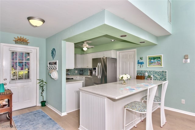 kitchen featuring white cabinetry, tasteful backsplash, appliances with stainless steel finishes, and kitchen peninsula