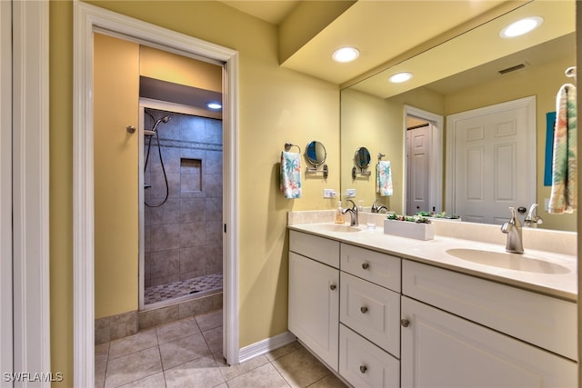 bathroom with tile patterned flooring, visible vents, a tile shower, and a sink