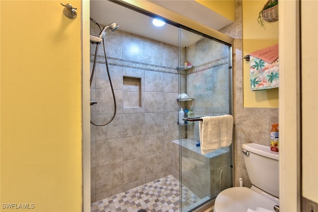 bathroom featuring toilet, a stall shower, and tile walls