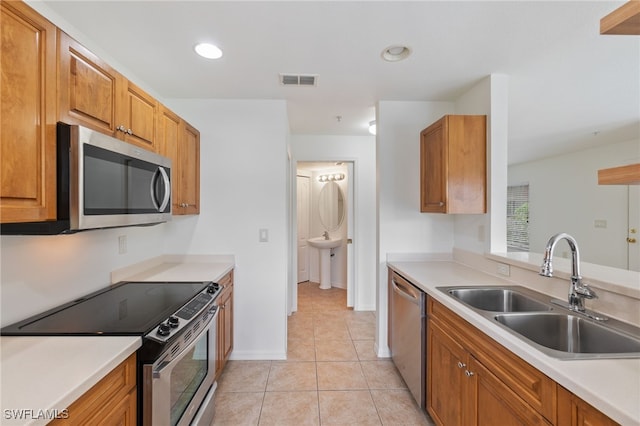 kitchen with light tile patterned floors, appliances with stainless steel finishes, sink, and vaulted ceiling