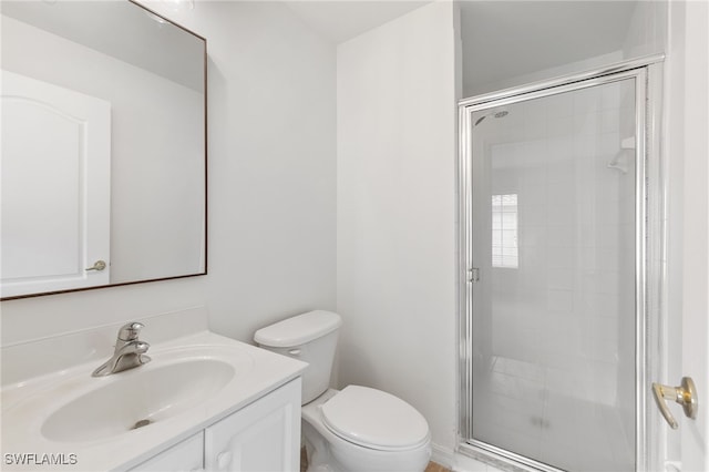 bathroom featuring toilet, vanity, and a shower with door