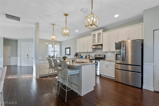 kitchen with decorative light fixtures, light stone counters, white cabinetry, and appliances with stainless steel finishes