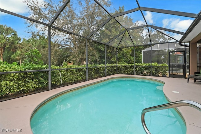 view of swimming pool featuring a patio area and glass enclosure