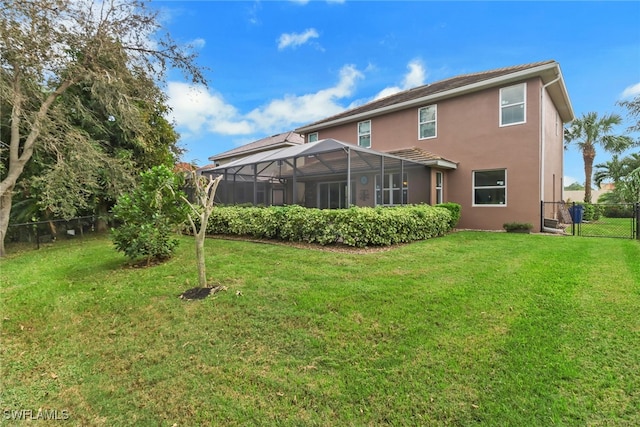 rear view of property with a yard and glass enclosure