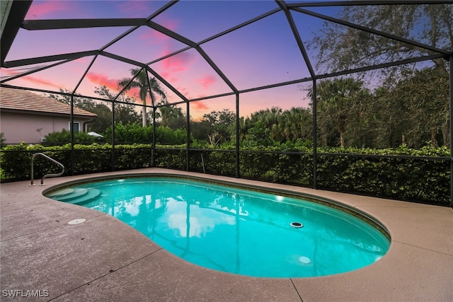 pool at dusk featuring a patio area and glass enclosure