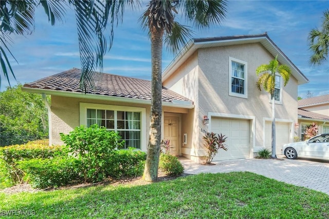 3555 Avion Woods Ct Unit 501, Naples, FL 34104 - view of front facade with a front yard, stucco siding, driveway, a tiled roof, and an attached garage