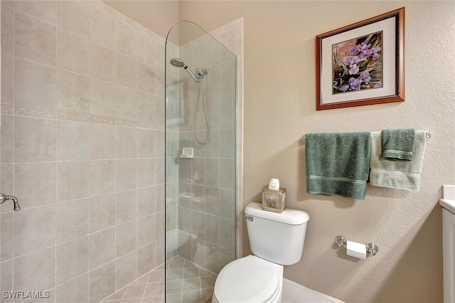 bathroom with a tile shower and toilet