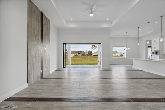 foyer with light hardwood / wood-style floors, sink, a tray ceiling, and ceiling fan with notable chandelier