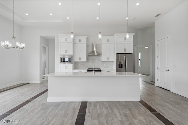 kitchen featuring appliances with stainless steel finishes, hanging light fixtures, light hardwood / wood-style floors, and a large island