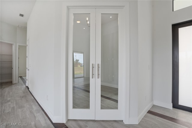 corridor with french doors and light hardwood / wood-style floors