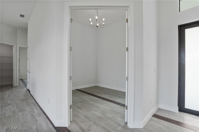 hallway featuring light hardwood / wood-style flooring and a chandelier