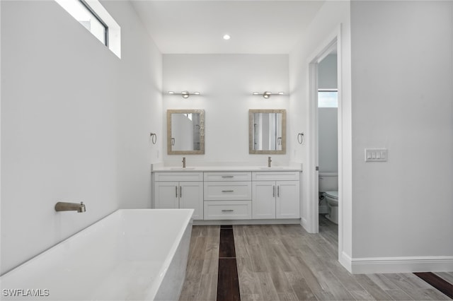 bathroom with vanity, a tub, toilet, and plenty of natural light