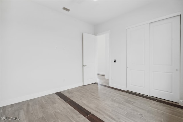 unfurnished bedroom with a closet and light hardwood / wood-style floors