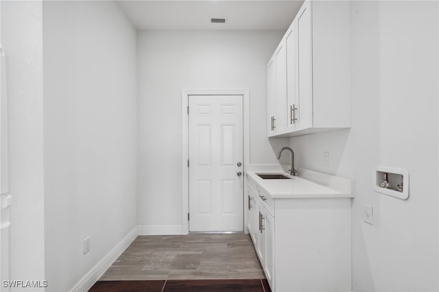 clothes washing area with hookup for a washing machine, hardwood / wood-style flooring, cabinets, and sink