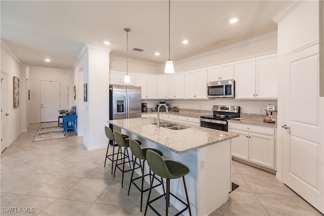 kitchen with an island with sink, stainless steel appliances, sink, light stone countertops, and white cabinets