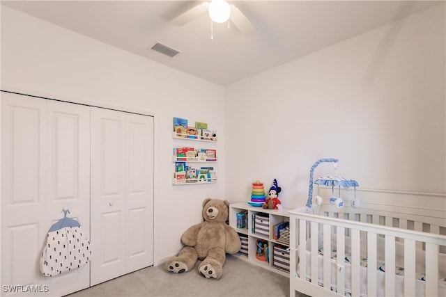 bedroom featuring a closet, a crib, carpet flooring, and ceiling fan