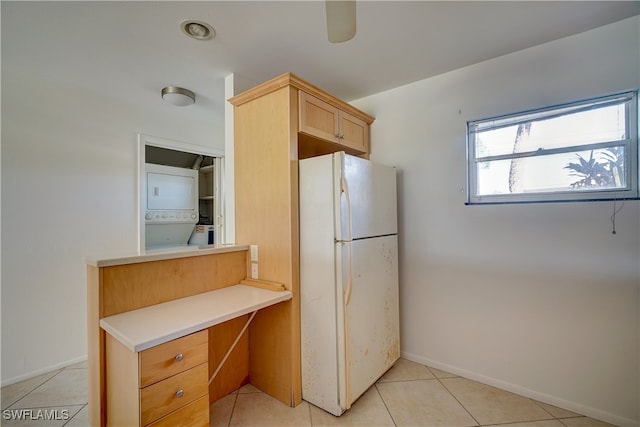 kitchen with white refrigerator, stacked washing maching and dryer, and light tile patterned floors