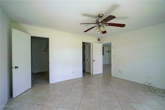 unfurnished bedroom featuring a spacious closet, a closet, ceiling fan, and light tile patterned flooring