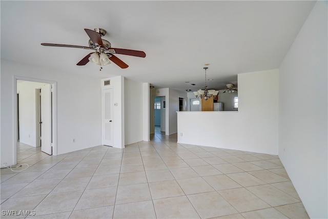 tiled spare room featuring ceiling fan with notable chandelier