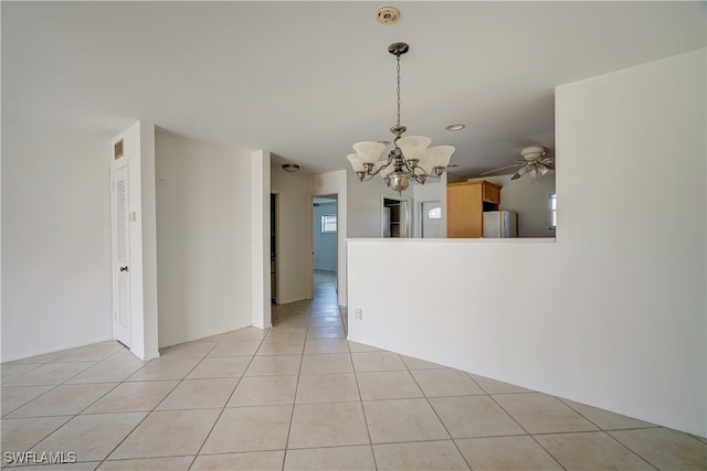 unfurnished dining area featuring light tile patterned floors and ceiling fan with notable chandelier