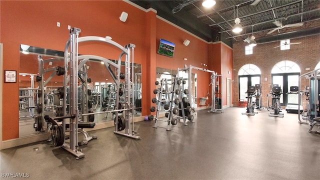 exercise room with a towering ceiling and brick wall