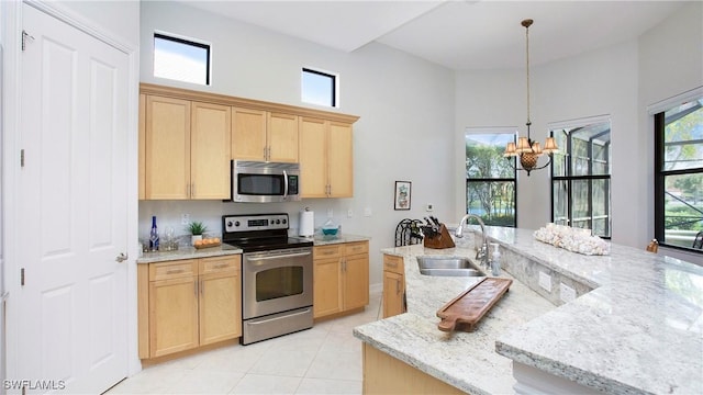 kitchen with light brown cabinets, sink, stainless steel appliances, and a chandelier