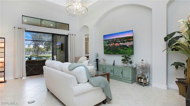 living room featuring light tile patterned floors, a high ceiling, and an inviting chandelier